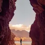 man sieht ein Felsentor, in der Mitte steht ein Mensch auf einem Stein, und symbolisiert Freiheit und Aufbruch