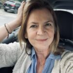 eine Frau, Karin, sitzt in einem Auto und schaut direkt offen und ehrlich in die Kamera