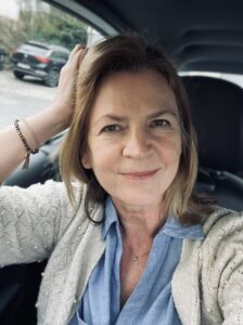 eine Frau, Karin, sitzt in einem Auto und schaut direkt offen und ehrlich in die Kamera