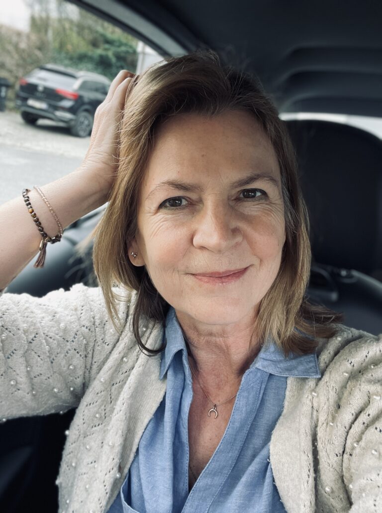 eine Frau, Karin, sitzt in einem Auto und schaut direkt offen und ehrlich in die Kamera