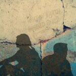 zwei Menschen sitzen am Boden, mit dem Rücken zueinander und schauen weg