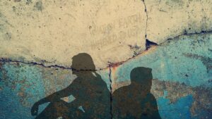 zwei Menschen sitzen am Boden, mit dem Rücken zueinander und schauen weg